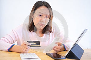 Confused portraitÃÂ young woman holding credit cards having problem online payment with credit card making rejected unsecure online